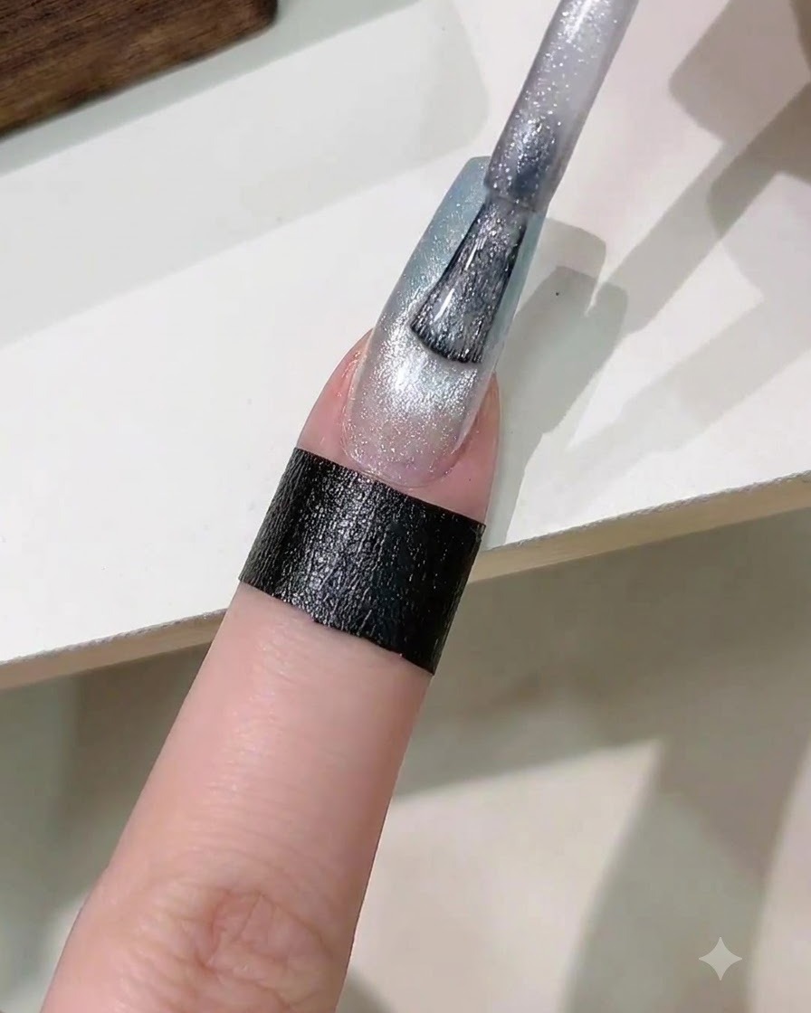 Un pennello che applica uno strato di smalto gel cat eye magnetico argentato sullunghia sfumata.