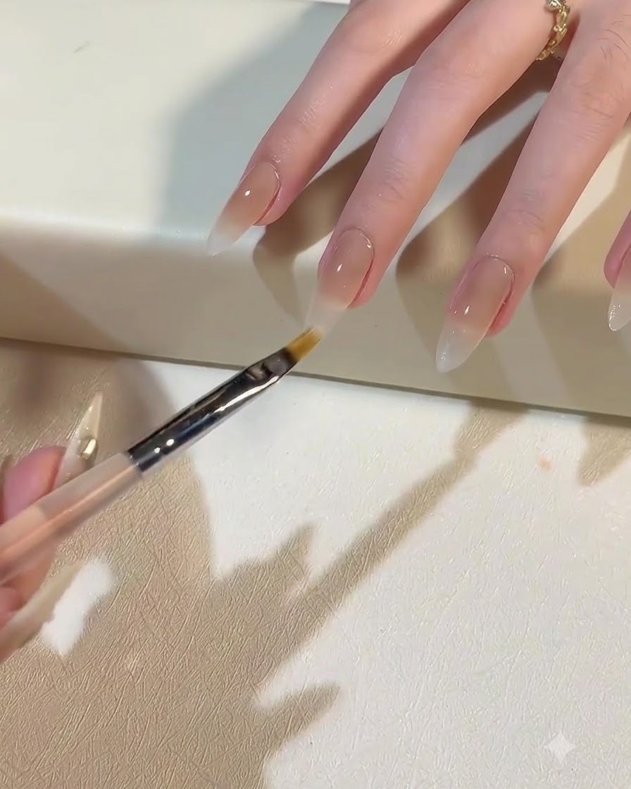 Un pennello applica il gel bianco latte per creare una sfumatura ombre che si estende verso il basso.