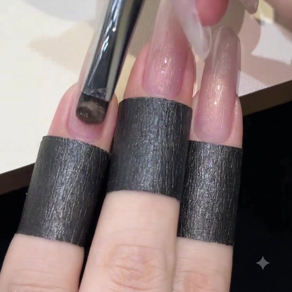 Un pennello in gel applica uno strato liscio e uniforme di smalto cat-eye rosa traslucido su una lunga ricostruzione per unghie trasparente.