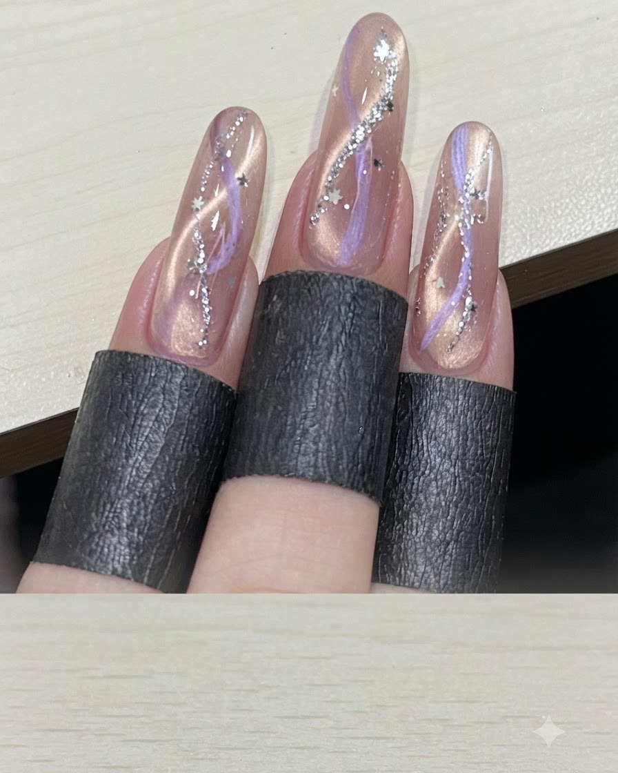 Una vista su più dita che mostra manicure cat-eye a nastro finite e impreziosite con paillettes argentate a forma di stella.