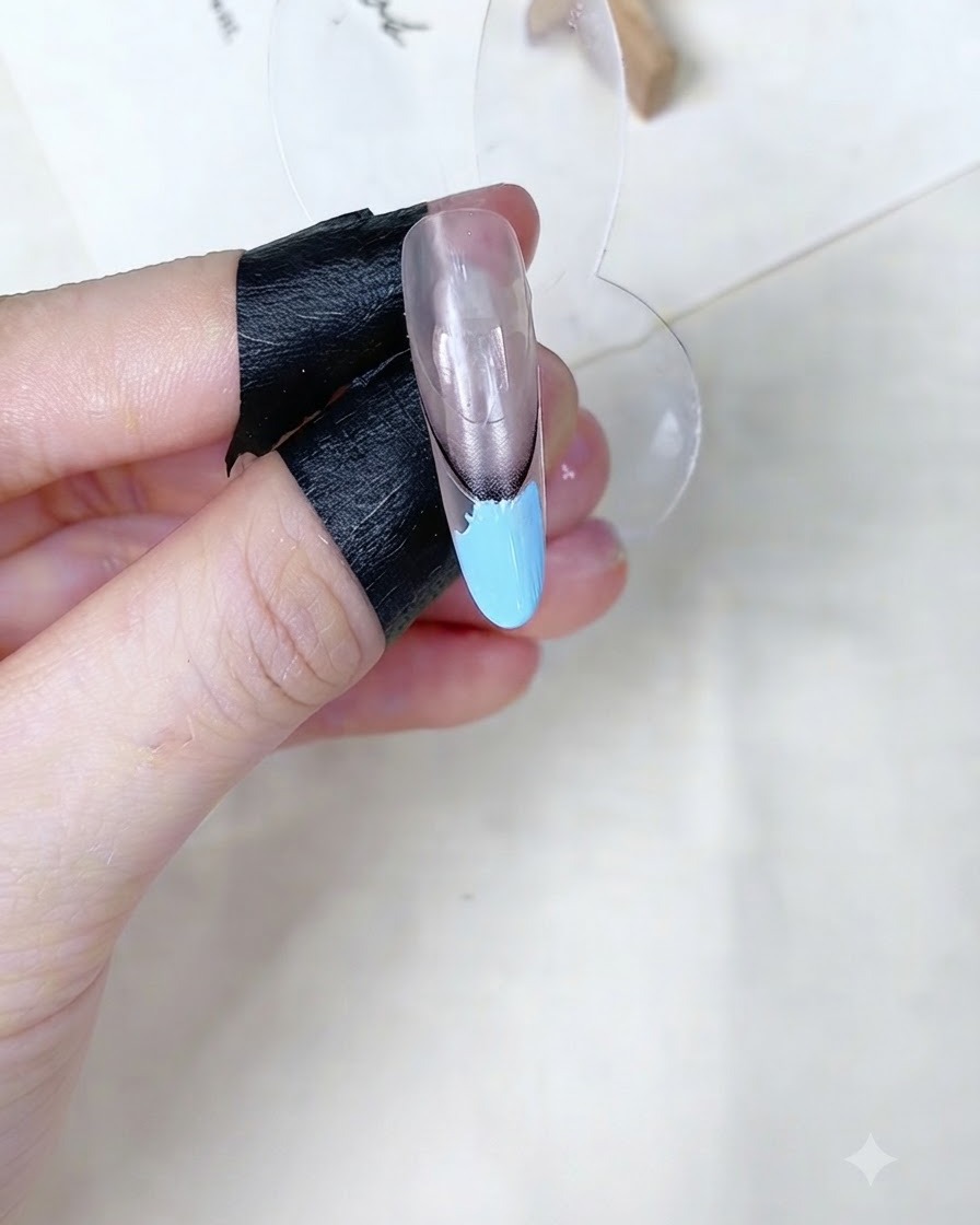 Una spugnetta per trucco che tampona larea in gel baby blue su un supporto per unghie.