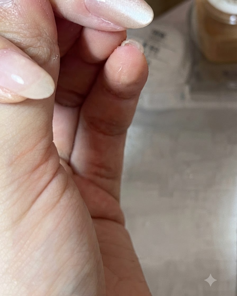 Primo piano di una mano che tiene una calamita in diagonale sopra ununghia laccata con gel nude per modellare il riflesso di luce.