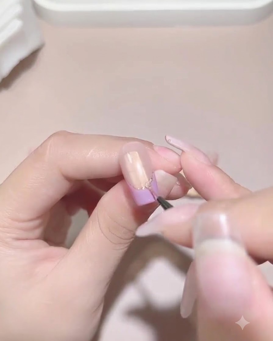 Un pennello fine da dettagli applica con cura il gel sigillante attorno alla base delle perle e degli strass su ununghia.