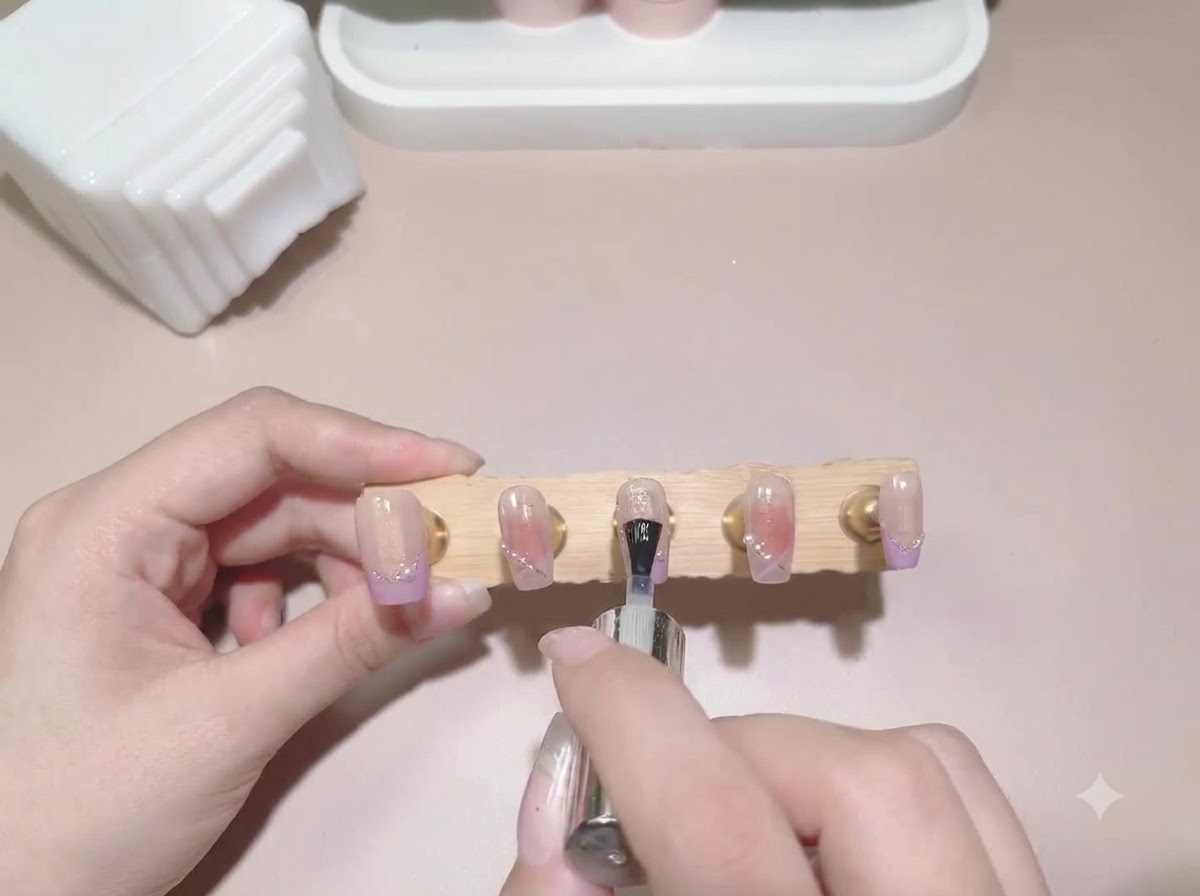 Un pennello applica il top coat sulle unghie finte precedentemente dipinte sullespositore.