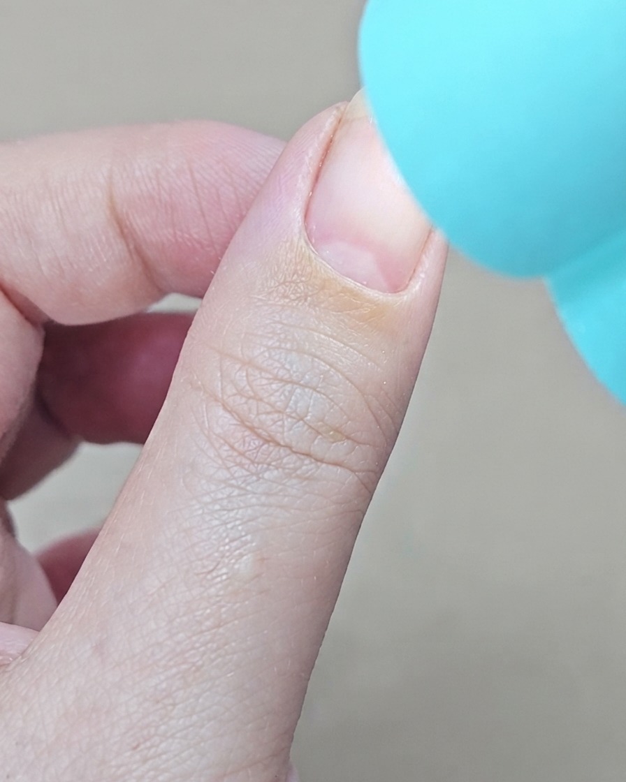 Una lampada UV blu tascabile posizionata direttamente sopra un dito per polimerizzare la base gel.