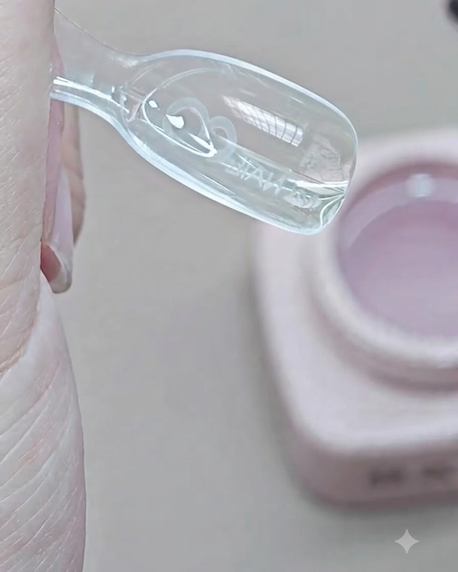 Un pennello posiziona il gel di extension trasparente nellincavo interno di uno stampo dual form trasparente.