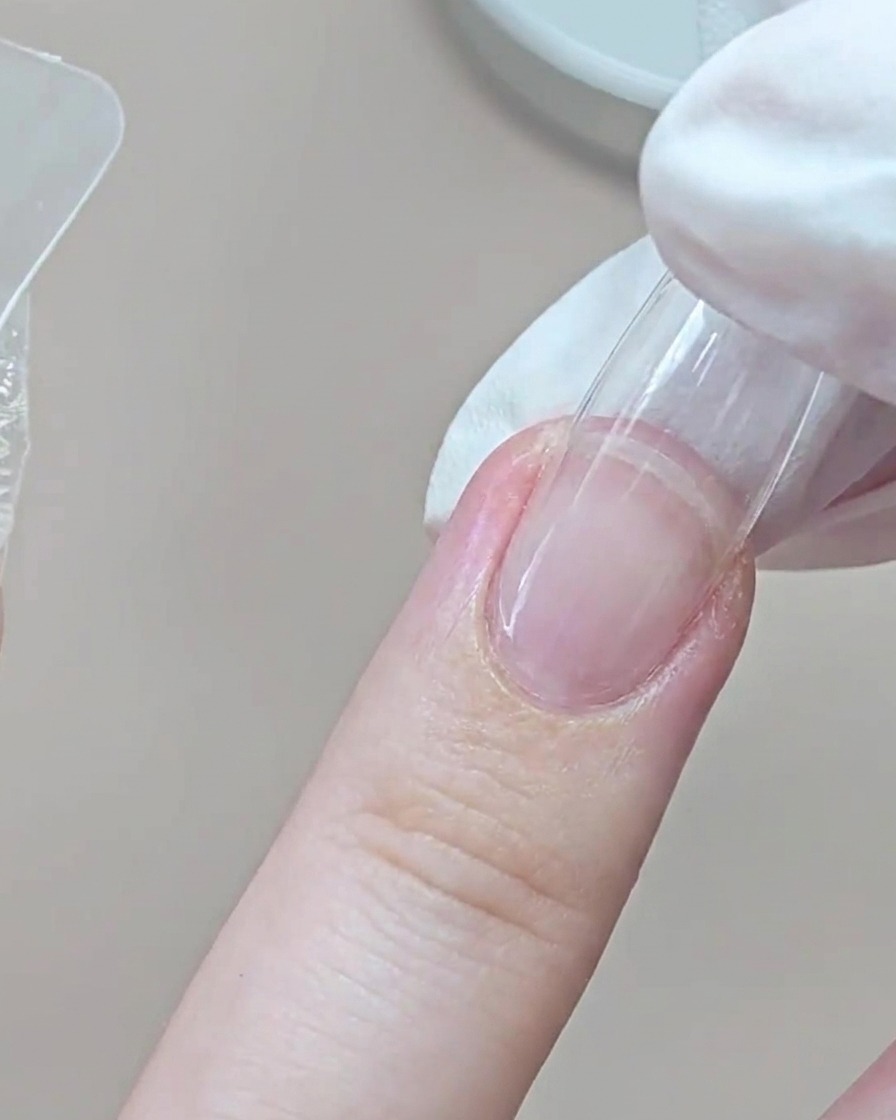 Un dito guantato preme una dual form trasparente sullanulare vicino alla zona delle cuticole.