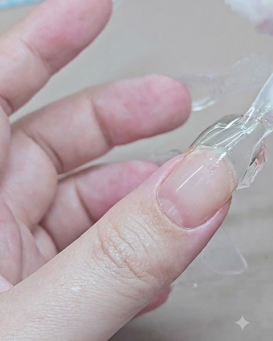 Una mano pizzica e solleva una dual form in plastica trasparente da unextension in gel polimerizzata sul dito indice.