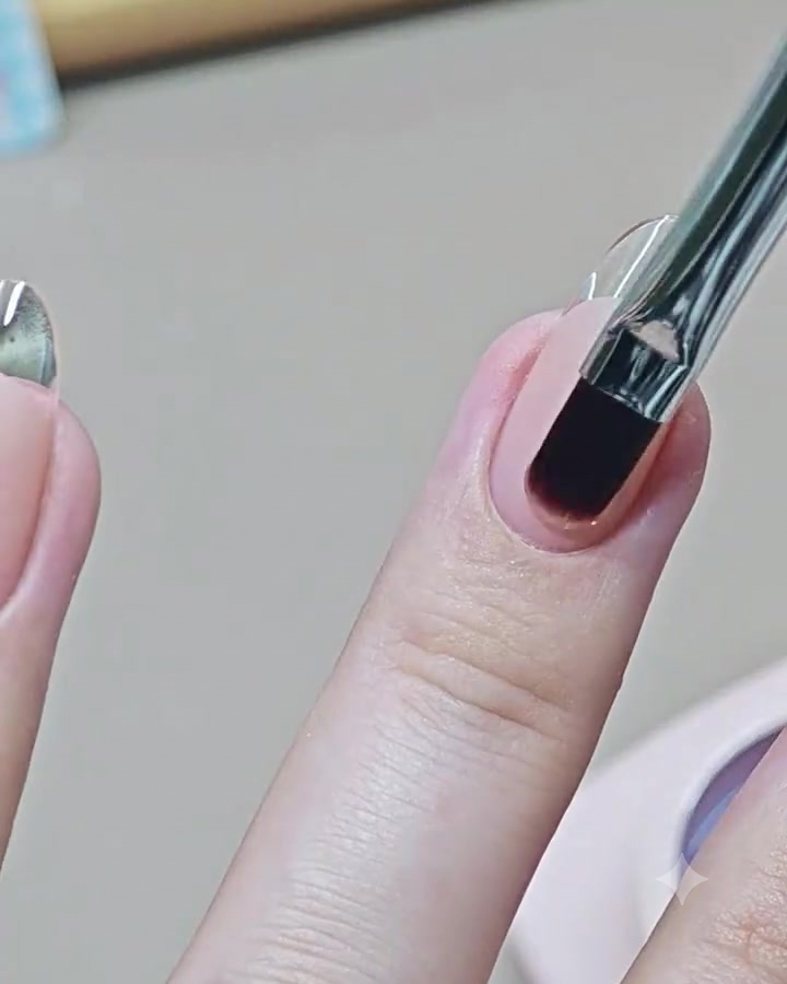 Un pennello per nail art applica un top coat trasparente lucido su ununghia finita con manicure French.