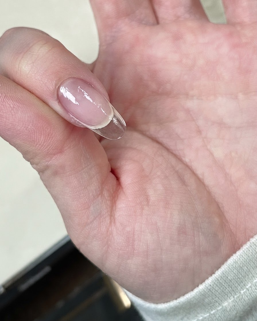 Una mano che tiene una tip trasparente sotto una mini lampada LED per la polimerizzazione.