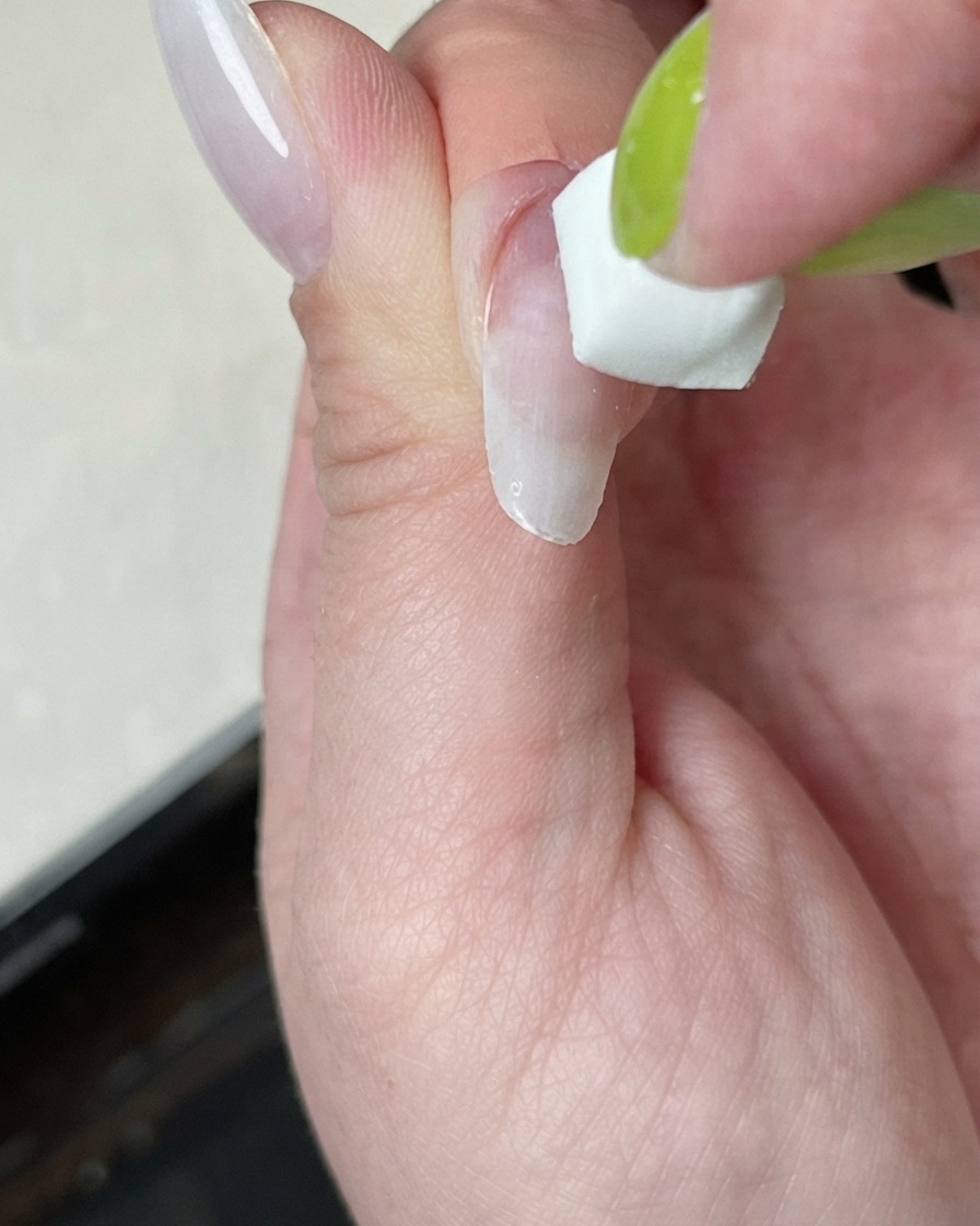Ununghia in fase di polimerizzazione sotto una mini lampada con un alone di luce bianca.