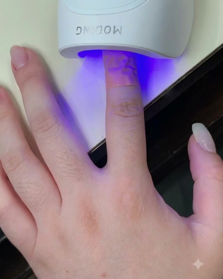 Un dito inserito allinterno di una mini lampada UV LED bianca con una luce blu che illumina lunghia.