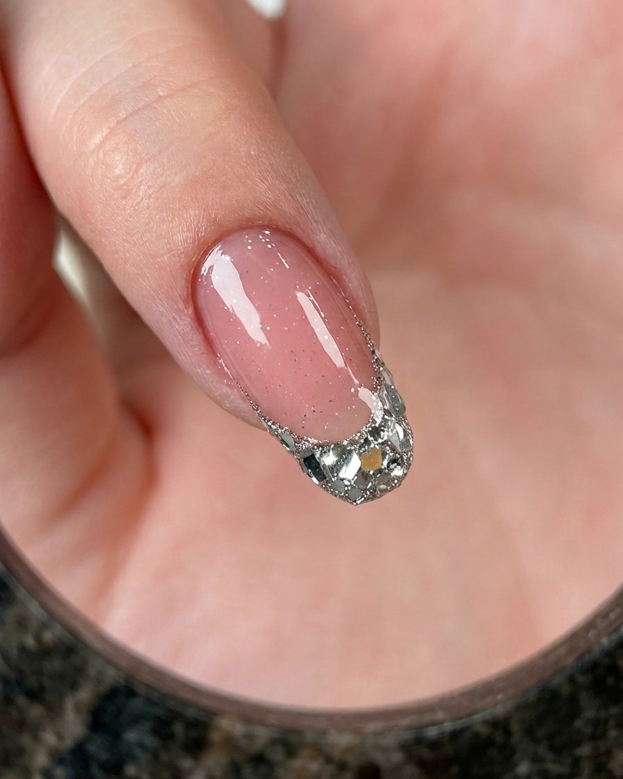 Una vista ravvicinata di un dito che mostra una french tip riempita di glitter argento chunky su base rosa.