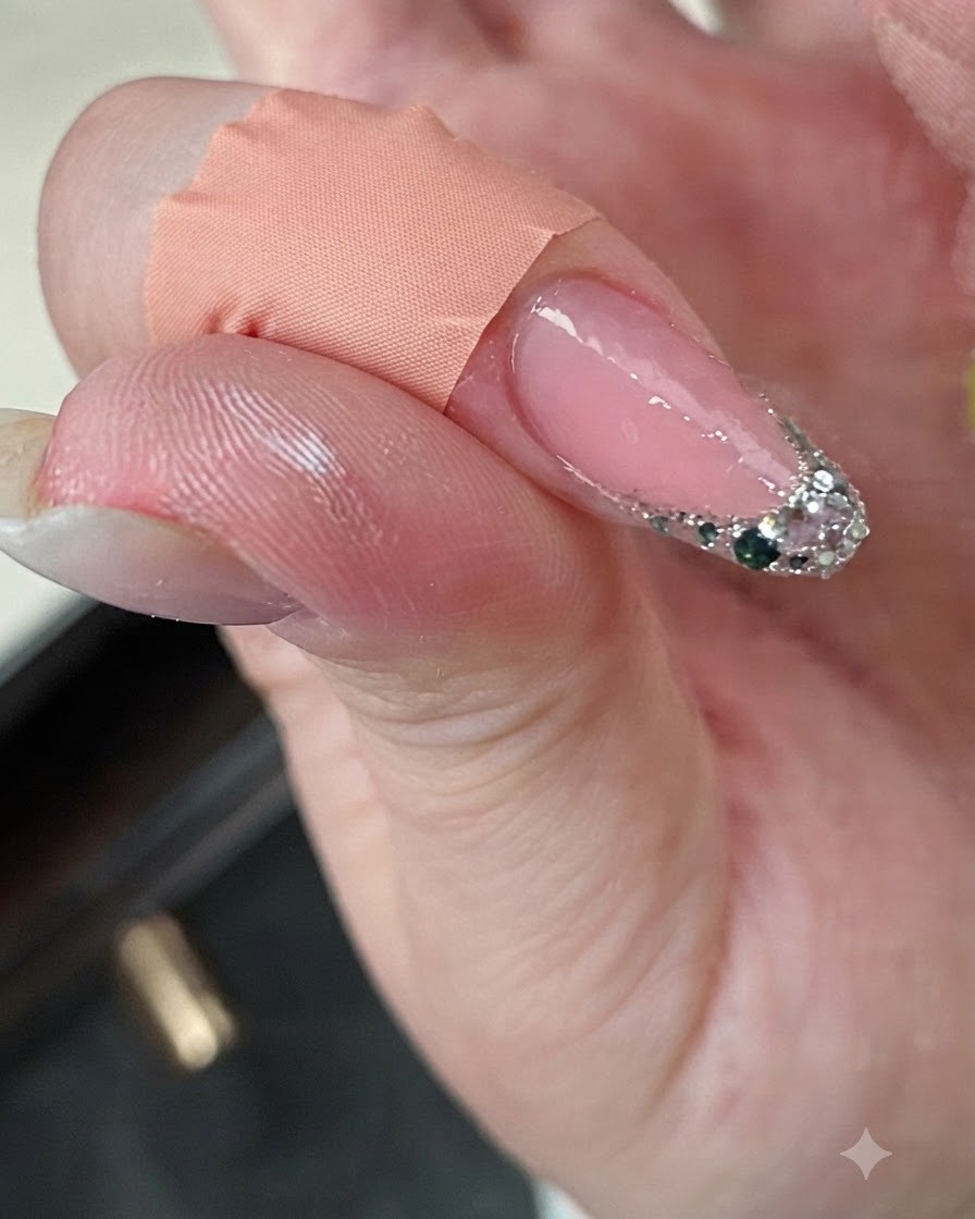 Un dito con french glitterata posizionato vicino a una mini lampada UV durante il processo di polimerizzazione.