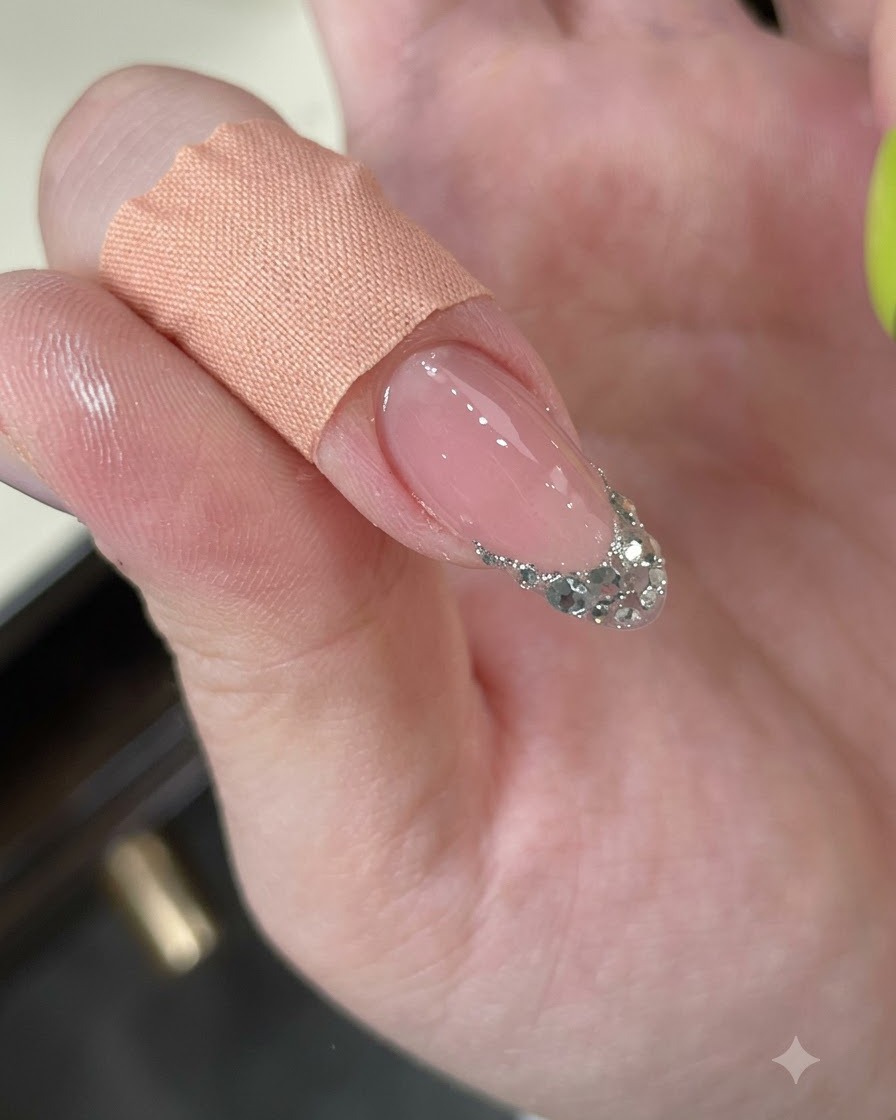 Un dito che viene pulito con un pad detergente, mostrando una french tip in glitter argento texturizzata.