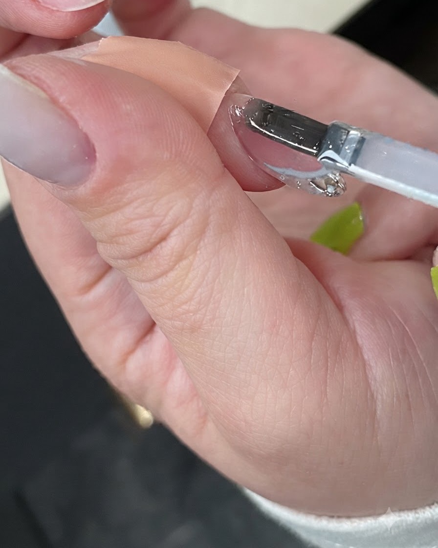 Una mano che polimerizza la manicure finita allinterno di una lampada per unghie UV bianca compatta.