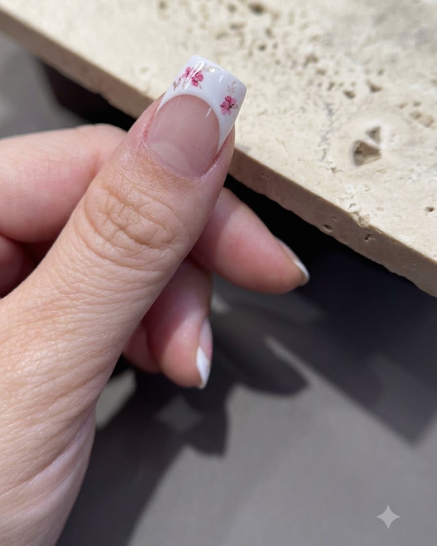 Primo piano di una pinzetta che stacca la carta di supporto da un foglio di adesivi floreali.