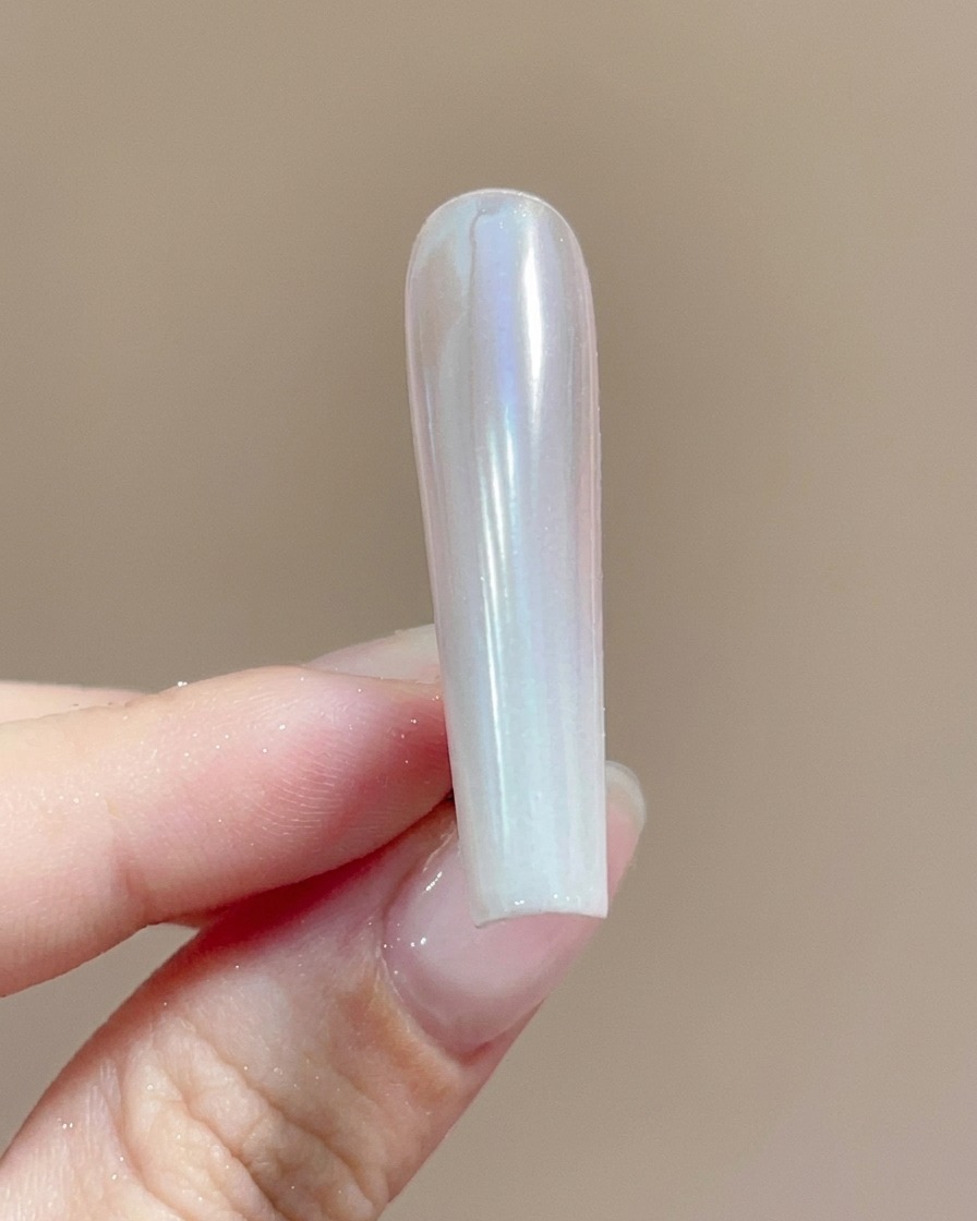 Un pennello che applica un top coat trasparente su ununghia rivestita di polvere chrome brillante.