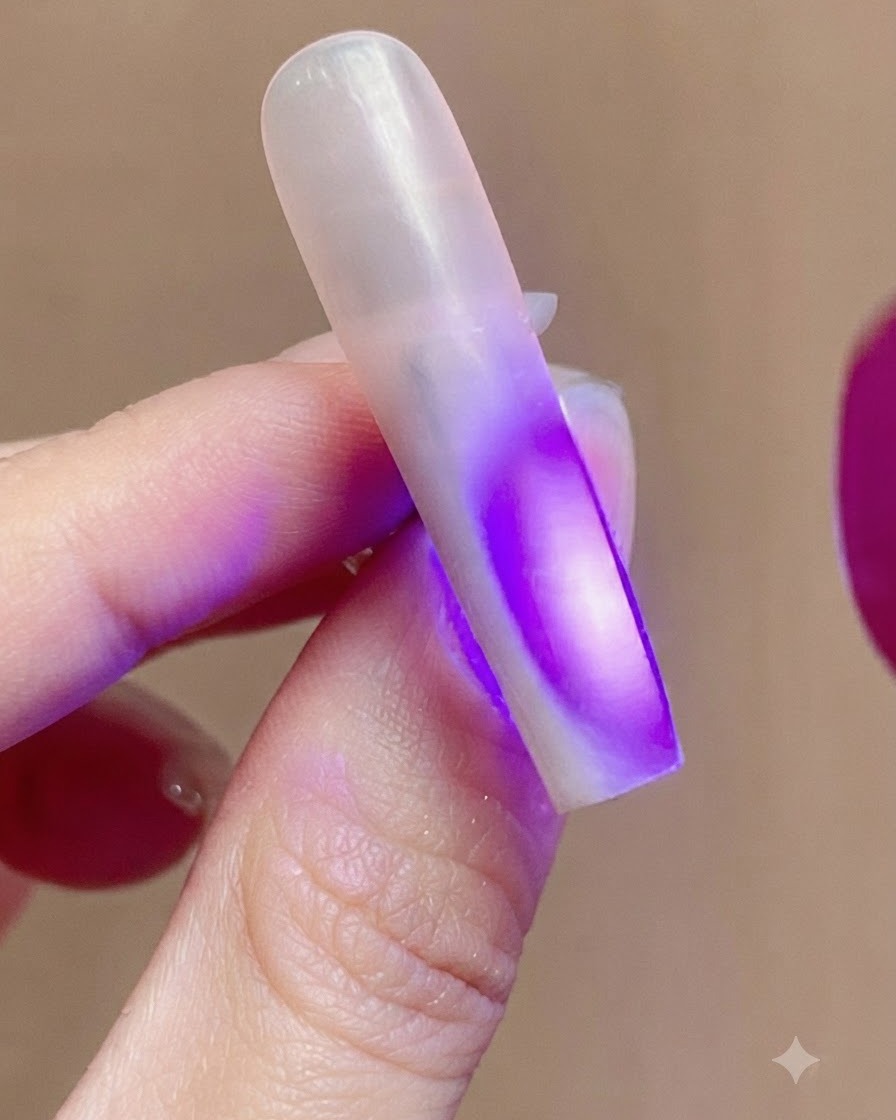 Ununghia illuminata dalla luce viola UV di una lampada per unghie durante il processo di polimerizzazione.