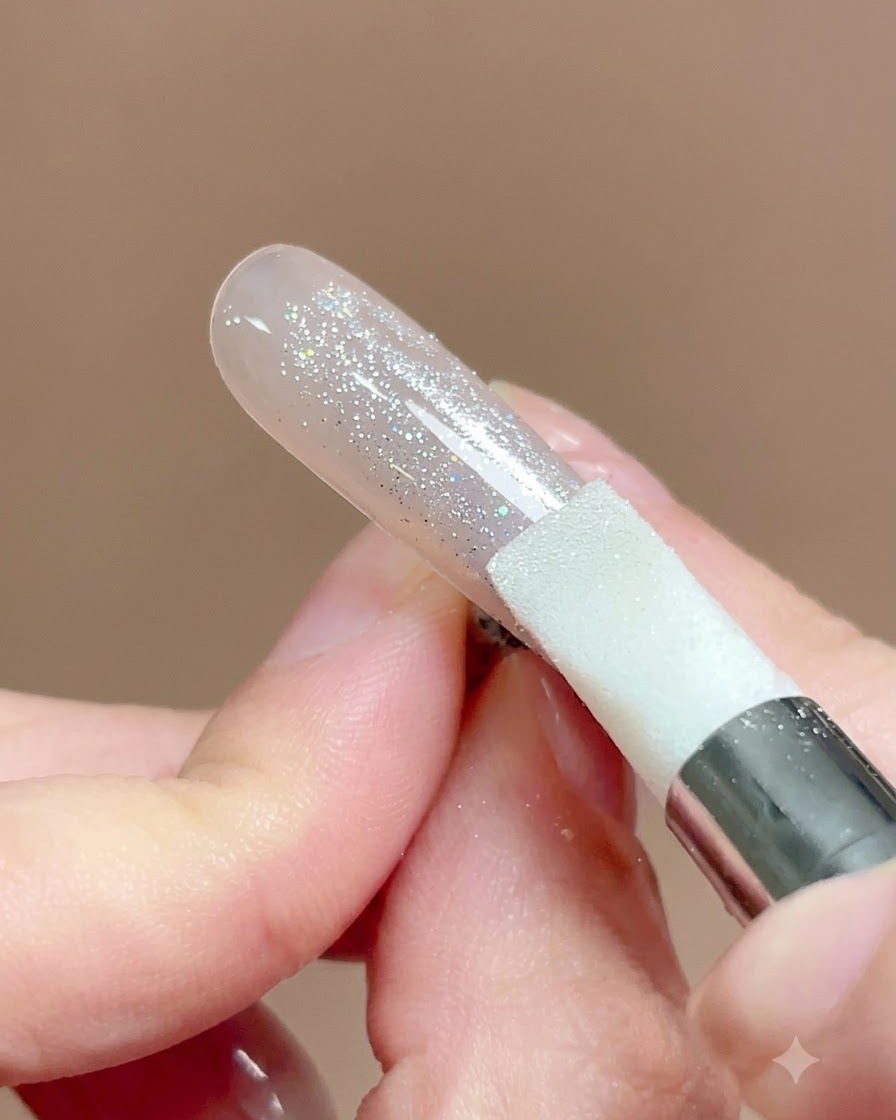 Uno strumento penna in silicone che viene premuto e strofinato sulla superficie di ununghia ricoperta di polvere chrome.