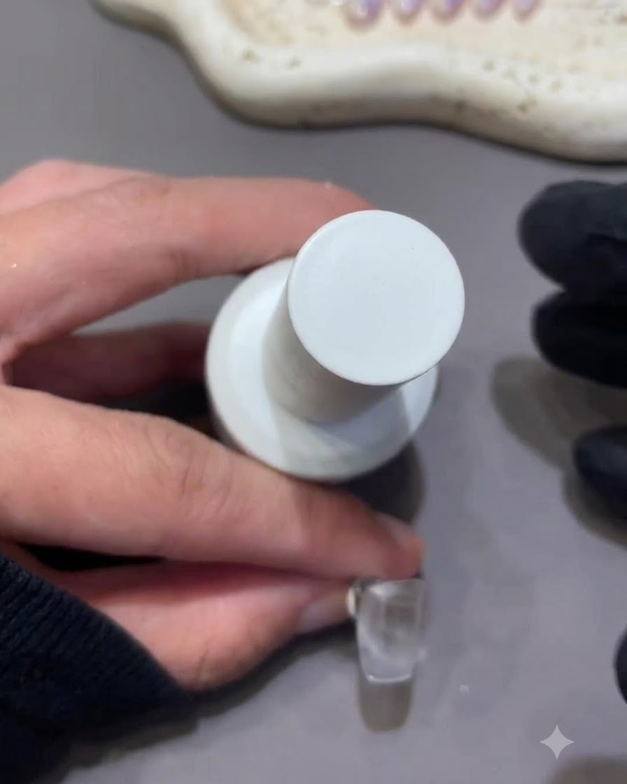Primo piano di un pennellino da unghie che regge un flacone di gel da scultura nude accanto a ununghia finta.