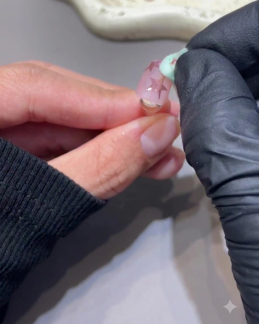 Una spugnetta pulita che rimuove delicatamente la polvere in eccesso da ununghia con stelle cromo rosa.