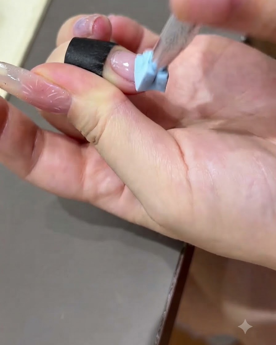 Una mano che preme una striscia nera di pratica sulla superficie di un piattino unghie di prova.