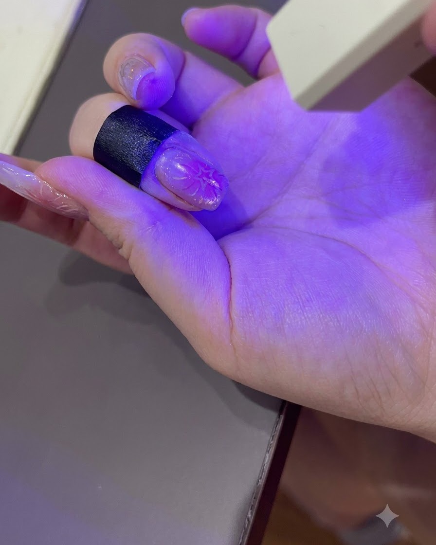 Una mano curata che polimerizza sotto la luce viola di una lampada UV/LED portatile per unghie.