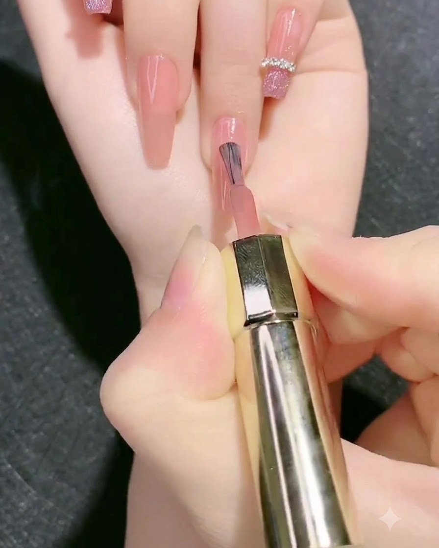 Un pennello applica un secondo strato di gel base rosa nudo sullunghia.