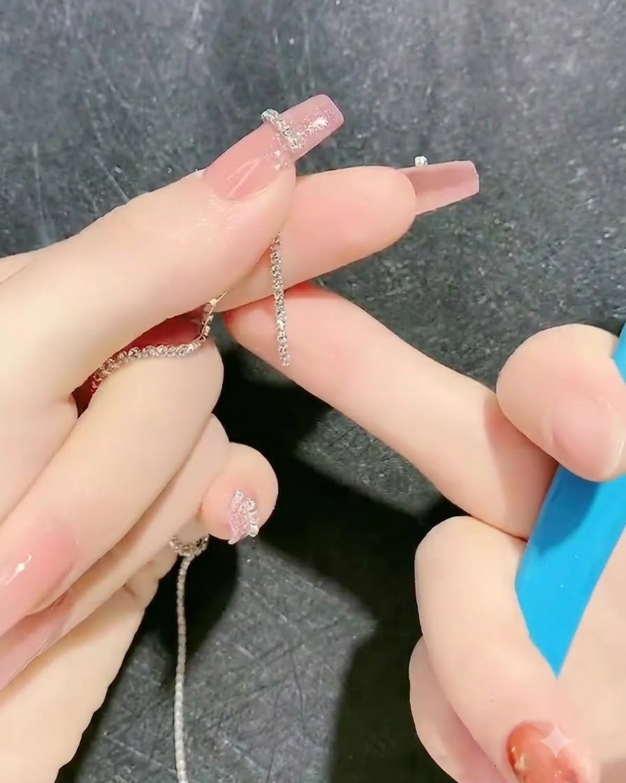 Uno strumento posiziona una striscia di catena di strass sul contorno in gel appiccicoso di un dito.