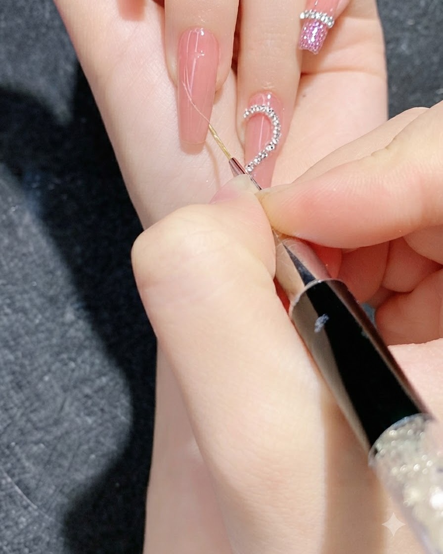 Primo piano di una sessione dettagliata di nail art che utilizza uno strumento fine per premere strisce di catena di strass su ununghia sfumata.