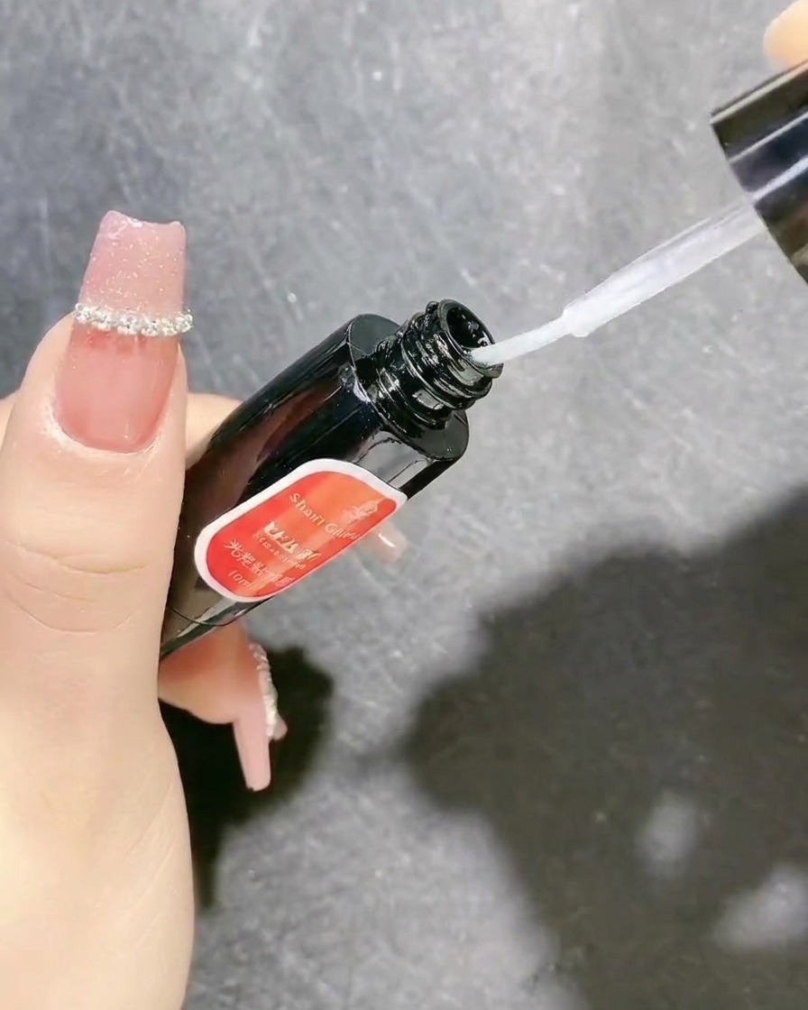 Un flacone di gel sigillante trasparente con pennello applicatore viene utilizzato per fissare le decorazioni per unghie.