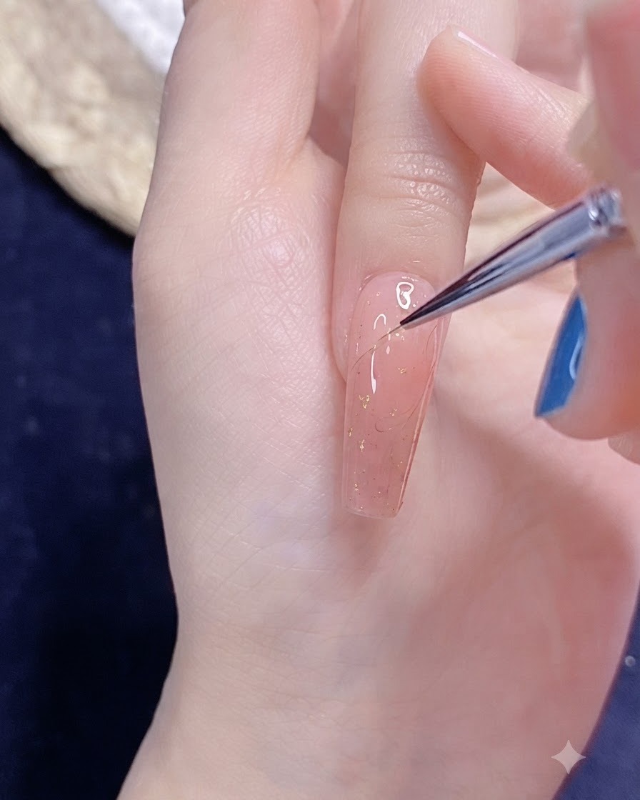 Un pennello fine per nail art che disegna il delicato contorno di mezzo cuore in gel su ununghia smaltata di rosa.