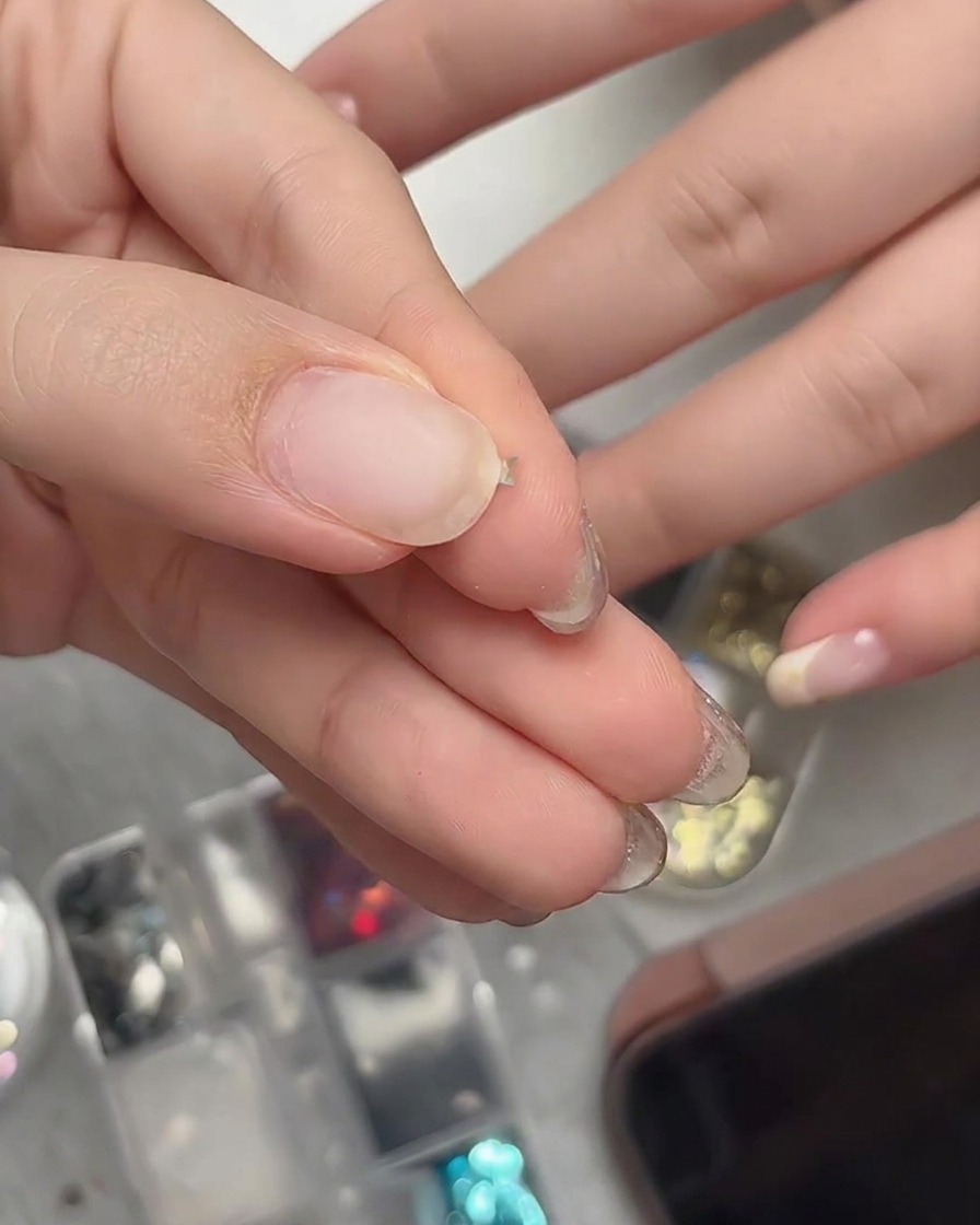 Dita che stringono delicatamente un minuscolo pezzo di glitter a stella per piegarlo in una forma tridimensionale curva.