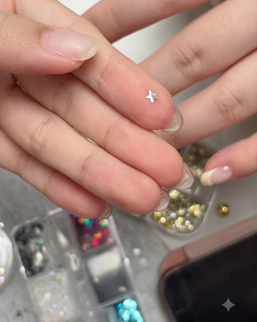 Un pezzo di glitter a stella argento metallizzato curvo appoggiato su un polpastrello, pronto per essere raccolto.