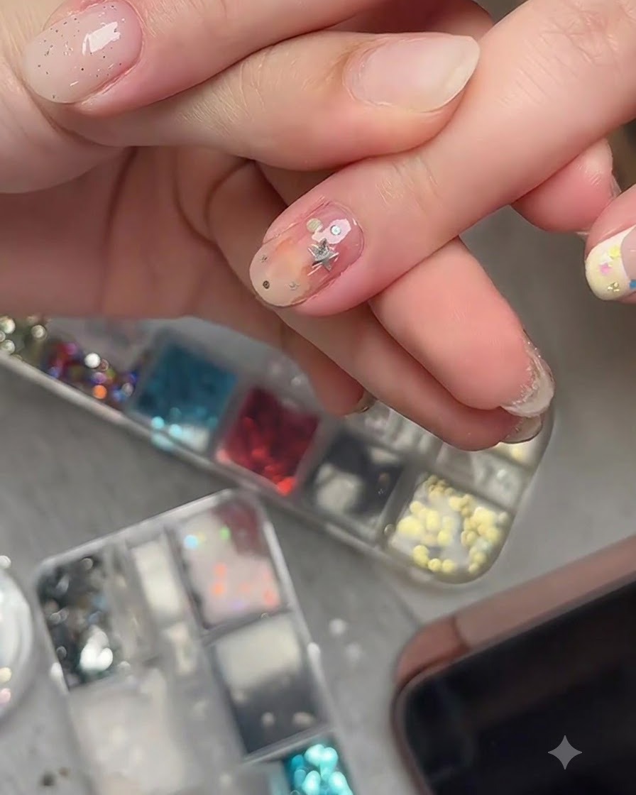 Un pennello da nail art che applica un top coat trasparente sopra pezzi di glitter a stella incorporati su ununghia finita.