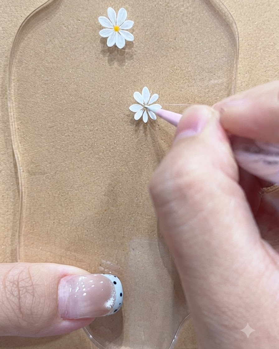 Un pennello a punta fine che disegna petali delicati per un motivo di margherita più piccolo su una tavolozza.