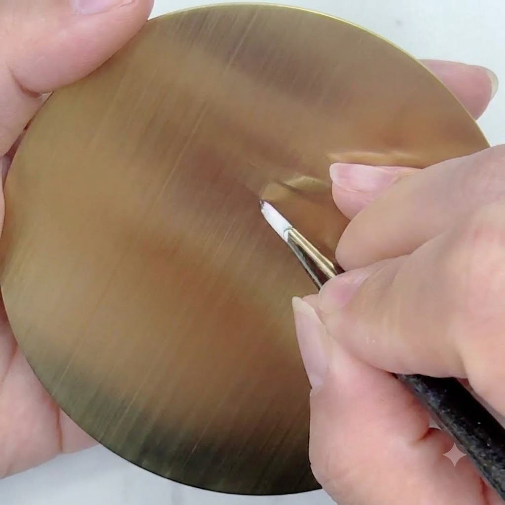 Un pennello liner sottile con gel bianco che disegna linee guida dritte e sottili che si irradiano da un punto centrale su una tavolozza circolare dorata per pratica.