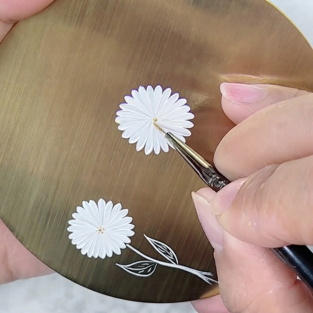 Un pennello fine-liner che posiziona un minuscolo punto dorato al centro di una margherita dipinta di bianco.