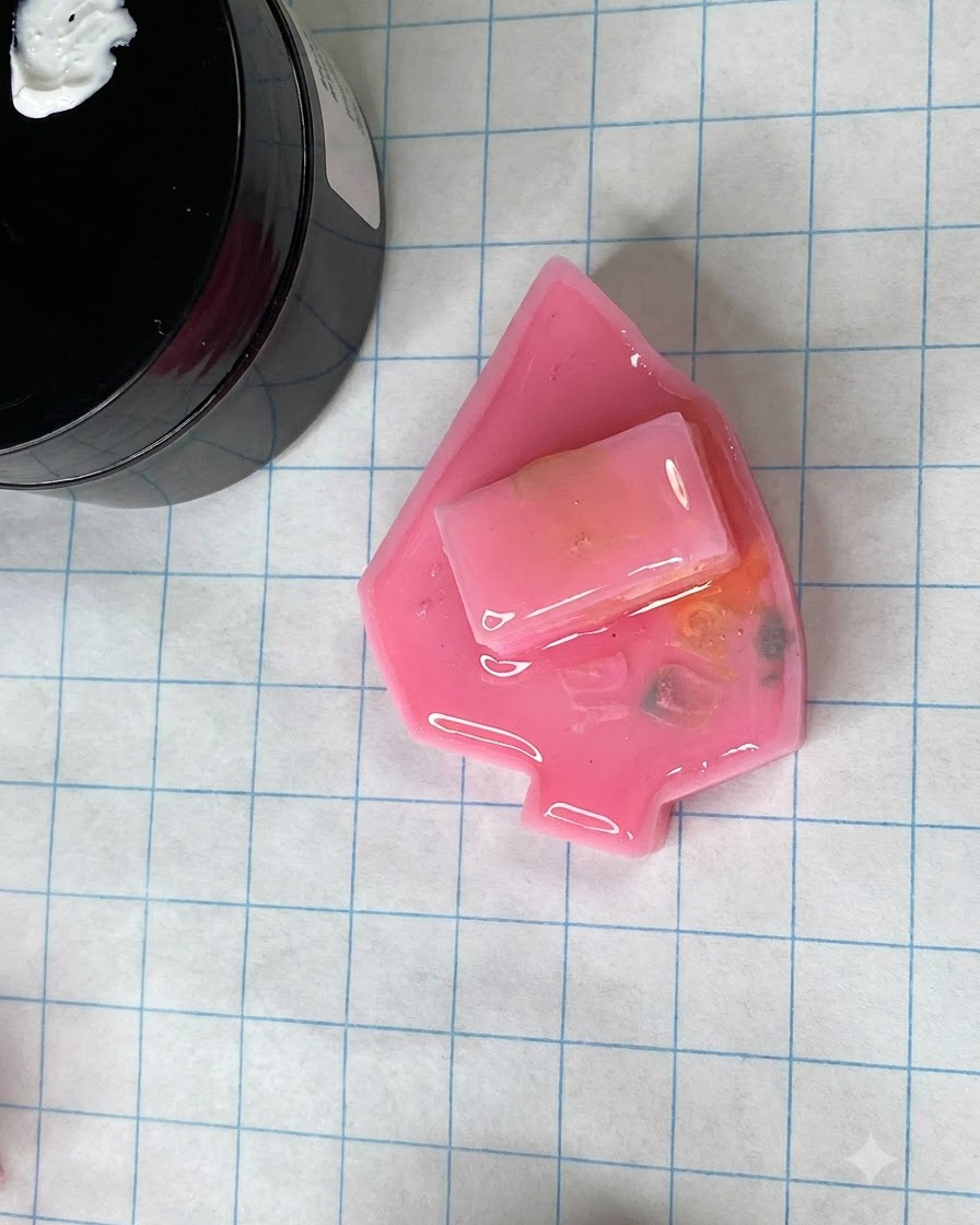 Uno stampo per unghie rosa opaco polimerizzato che poggia su un tappetino per lavori artigianali a griglia vicino a un barattolo di gel.