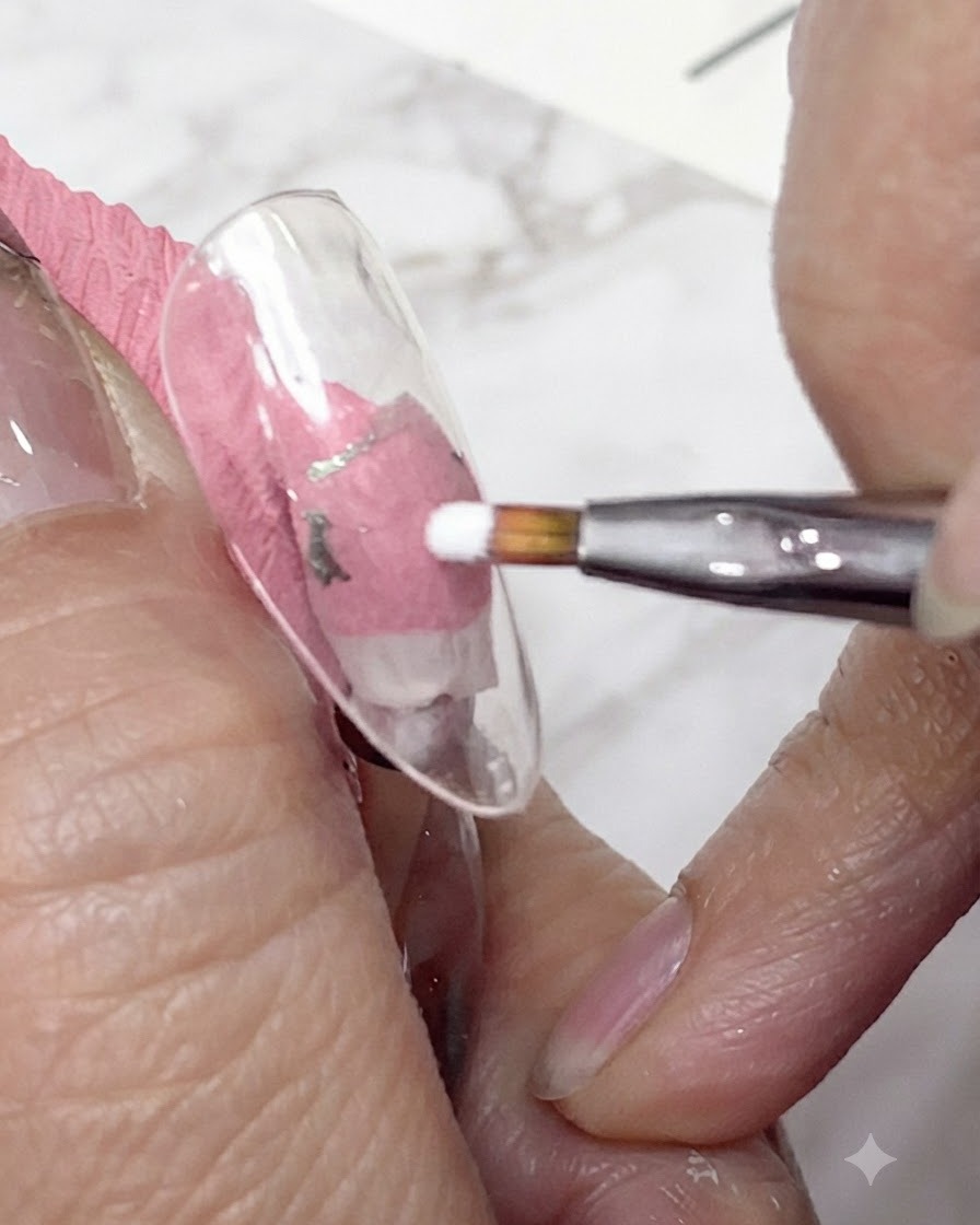 Un primo piano di un pennello liner fine che applica gel bianco per formare i primi petoli di una margherita su una tip per unghie trasparente.