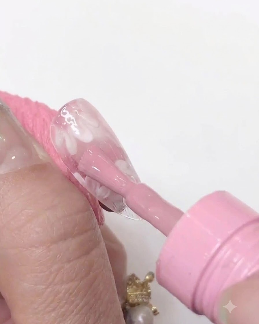 Una mini lampada per unghie UV/LED tenuta vicina a una tip trasparente per polimerizzare lo strato di gel rosa applicato.
