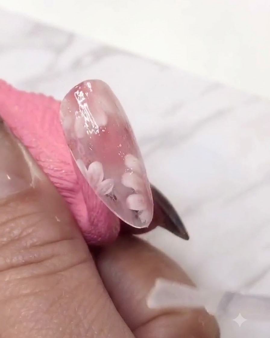 Un pennello liner fine che aggiunge un secondo strato di petoli di margherita bianchi sopra lo strato di gel colorato di rosa per dare profondità.