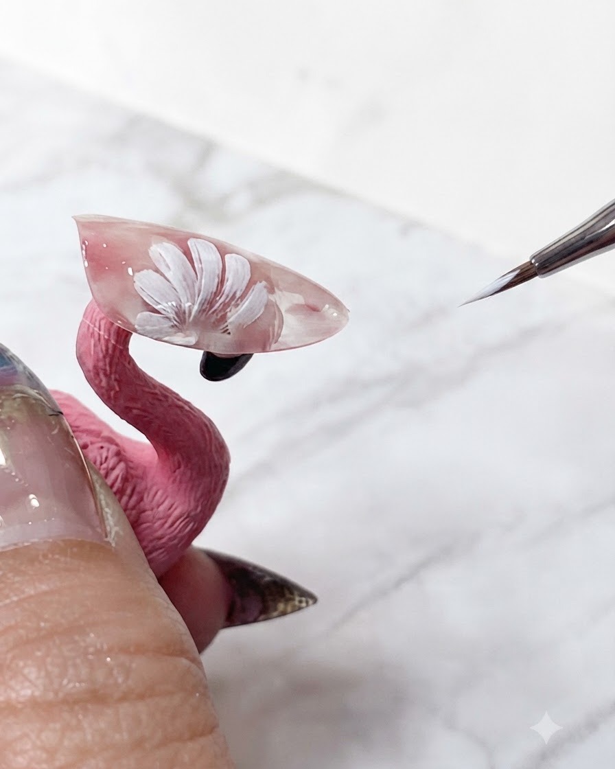Un pennello per nail art fine che ritocca le punte bianche nitide dei petoli di margherita stratificati su unextension rosa translucida.