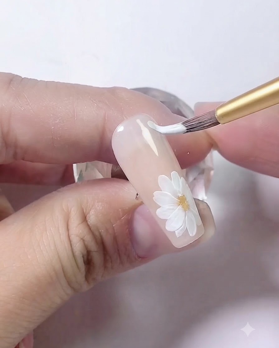 Un pennello da nail art che disegna due linee bianche curve e parallele lungo il bordo dellunghia.