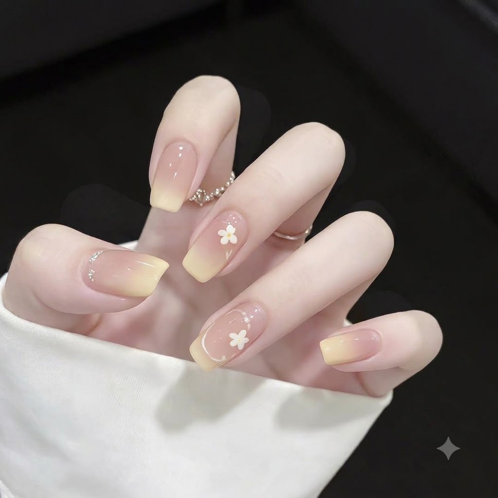 Primo piano di unghie quadrate con punte sfumate in giallo, sottili accenti di contorno French bianco e piccoli pois.