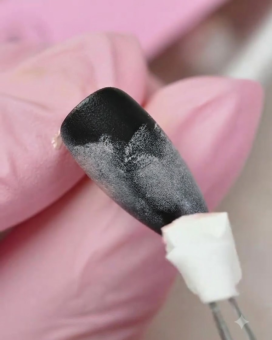 Un applicatore in spugna che tampona del gel giallo sulla parte inferiore di ununghia con texture sfumata nera e rosa.