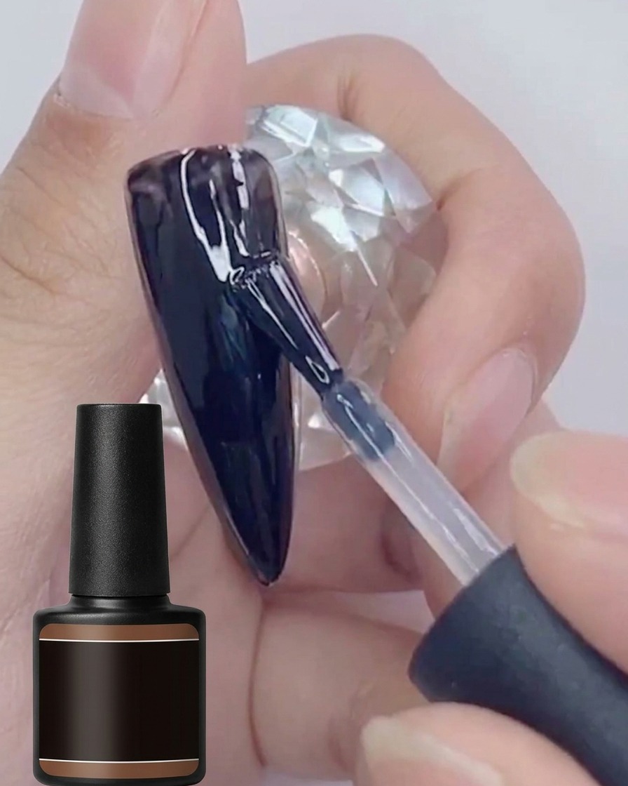 Un pennello applica una seconda mano di smalto gel nero lucido su una superficie dunghia dipinta di nero.
