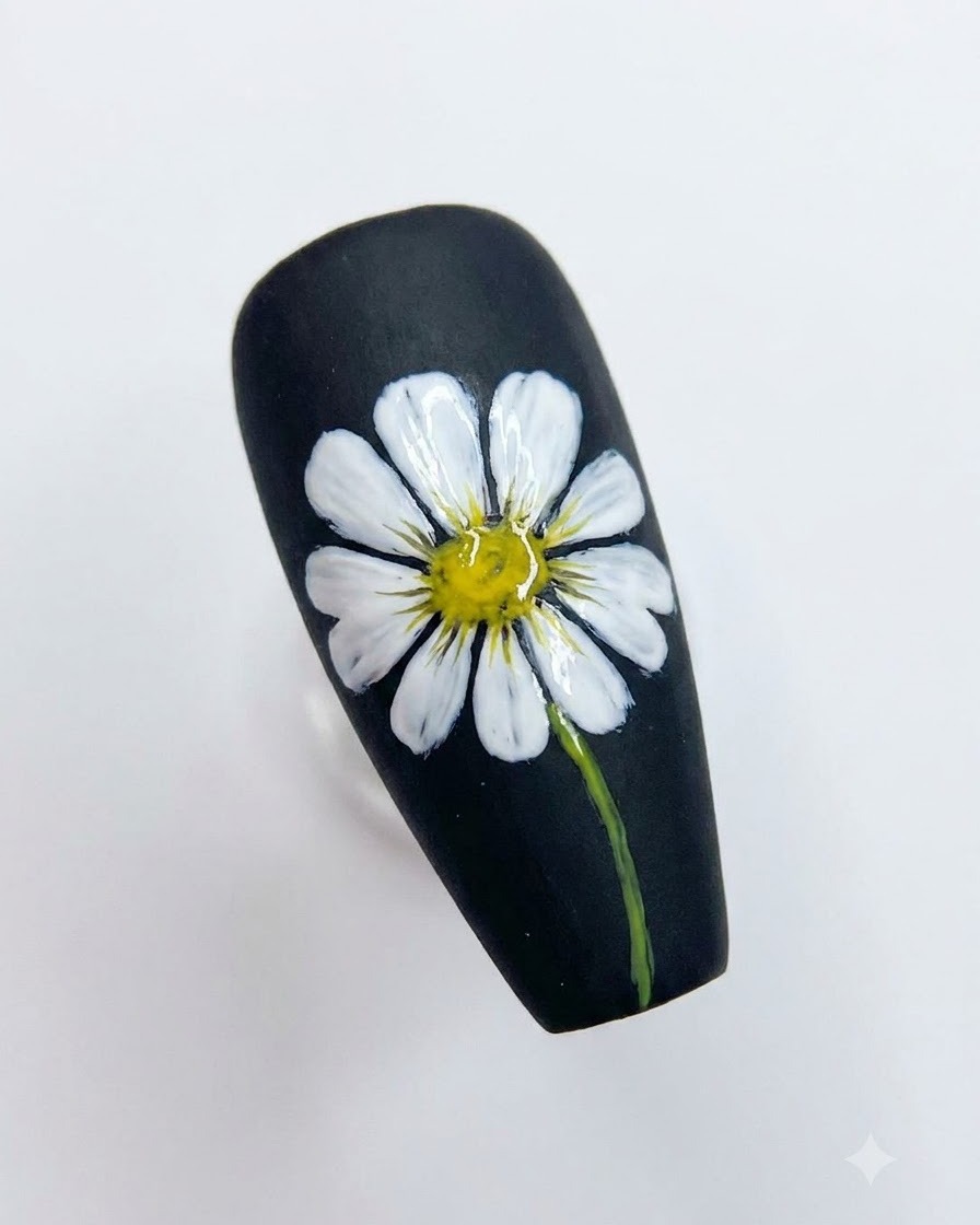 Un design di nail art su unghia nera completato che mostra una dettagliata margherita bianca con centro giallo brillante e stelo verde.