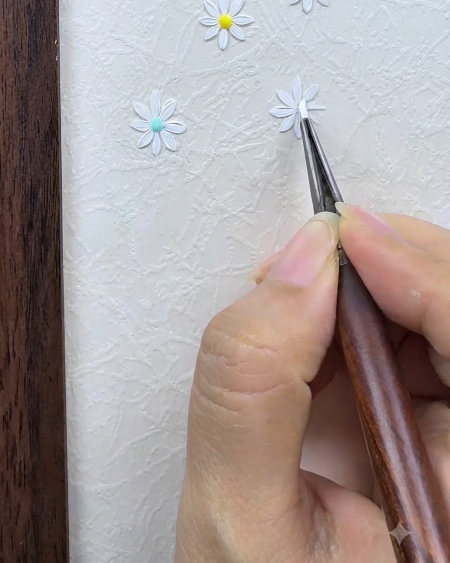Un pennello da dettaglio che delinea e rifinisce con cura i petali bianchi di una margherita dipinta su uno sfondo di nail art strutturato.